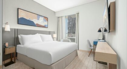 Spacious and elegant modern hotel room featuring a king size bed, contemporary artwork, and a city view.