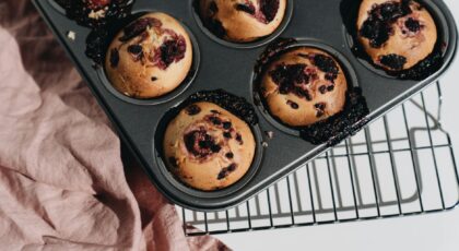Delicious berry muffins cooling on a rack with a rustic cloth backdrop, perfect for food lovers.