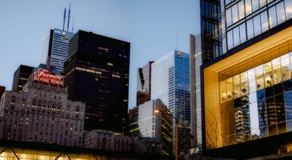 Famous hotel and multistory skyscrapers with glass walls located on street of modern district of Toronto city in evening time
