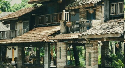 Charming country inn with rustic brick and wood architecture surrounded by lush greenery on a sunny day.