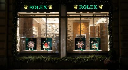 Nighttime view of a Rolex store with festive Christmas decorations and lights.