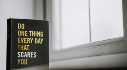 Rectangular shaped book with printed title on black hardcover on windowsill in house in daytime