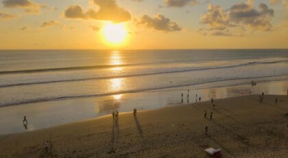 Beautiful sunset on Seminyak Beach, Bali with people enjoying the view and golden sands.