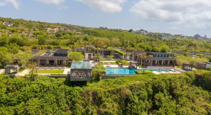Aerial view of a luxurious villa with an infinity pool on a cliffside in Bali, Indonesia.