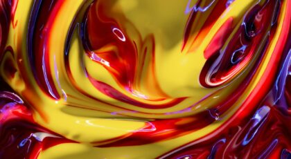 A close-up of colorful, swirling paint with vibrant yellow and red hues.