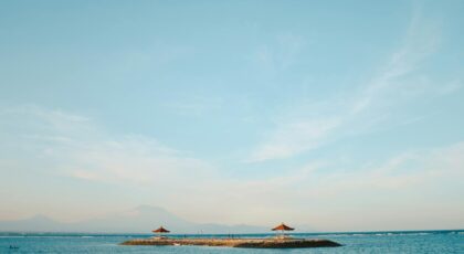 Tranquil island view with blue sky and calm ocean waters, perfect for relaxation imagery.