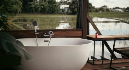 Relaxing outdoor bathtub setup with a scenic view of rice fields and lush greenery.