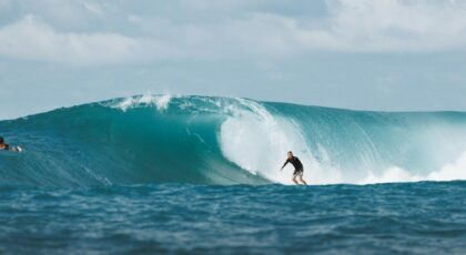 Surfer riding a massive ocean wave in Bali, capturing the thrill and beauty of water sports.