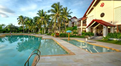 Sunny tropical resort with pool and palm trees, ideal for vacation escape.