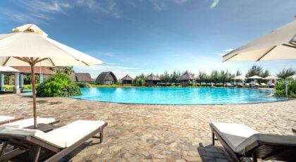 Serene poolside view with lounge chairs and umbrellas at a tropical resort, ideal for relaxation.